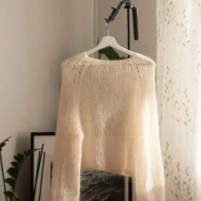 A cream knitted cardigan hanging on a hanger