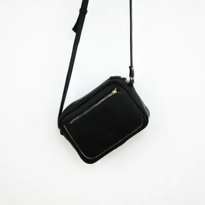 A small black crossbody bag with a long strap
